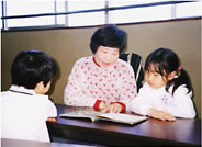 女性が子供二人に本を読み聞かせている写真